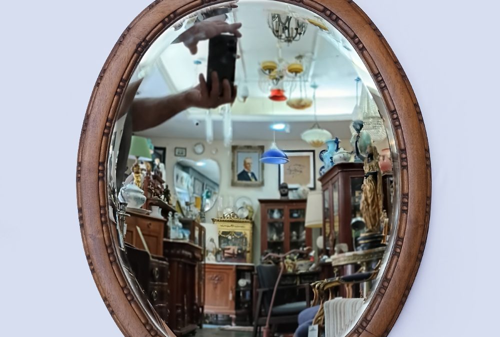 DI 68 – Espelho antigo oval em madeira entalhada com frontão floral e cristal bisotê