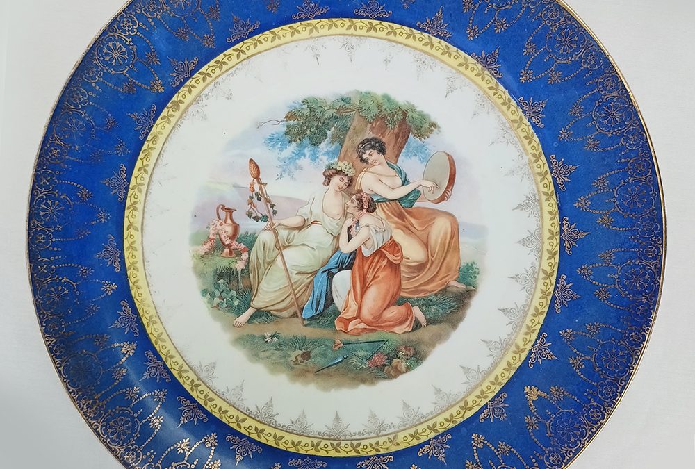 LO 102 – Prato antigo e grande em porcelana austríaca Royal Vienna borda azul e dourada com cena de damas em jardim