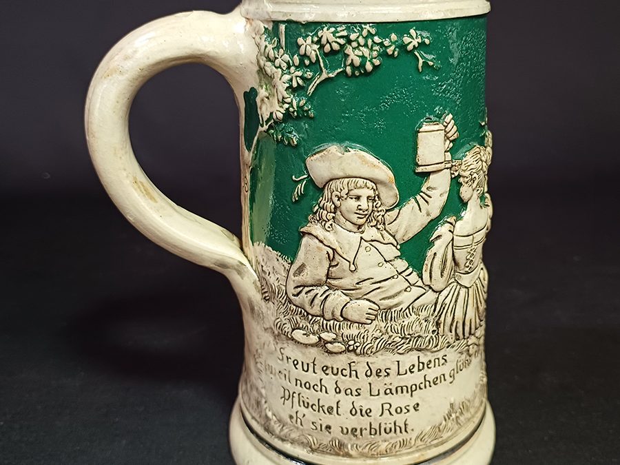 LO 321 – Caneco de cerveja ou Tankard alemão antigo em cerâmica com figuras em relevo e canção “Aproveite a Vida”